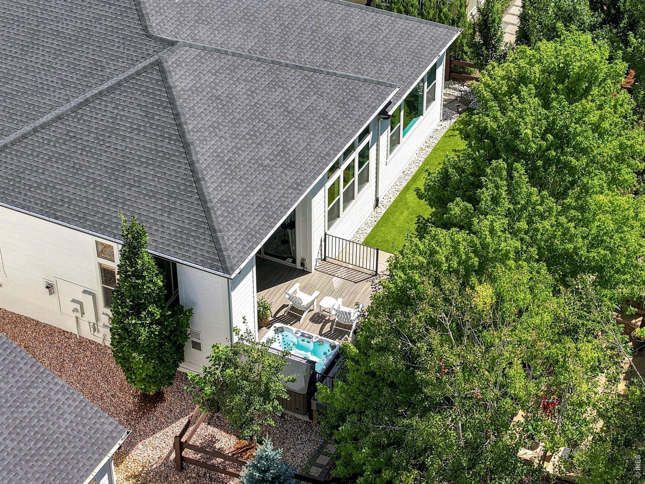 Aerial view of a landscaped home backyard with a deck, outdoor seating, and spa.