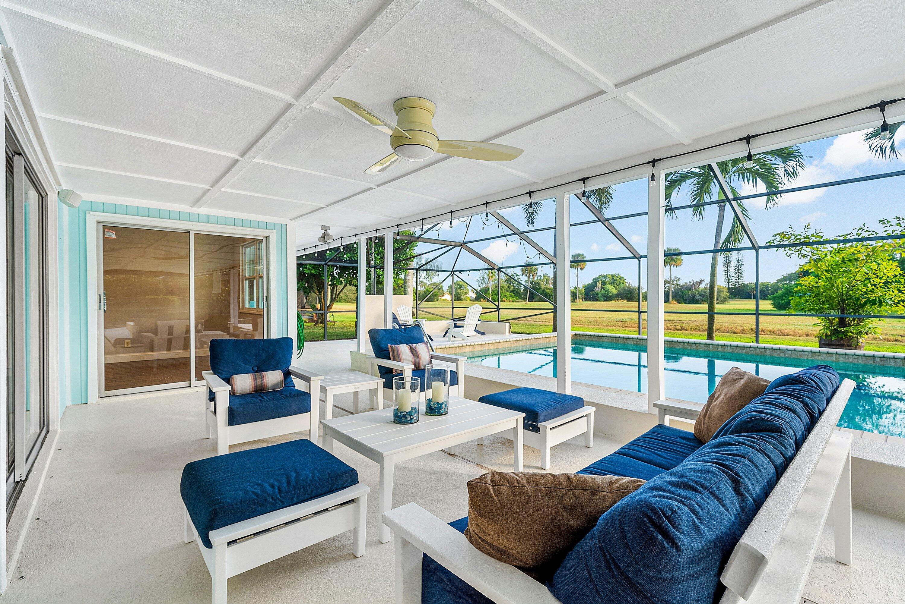 Screened patio with navy-cushioned seating beside a swimming pool.