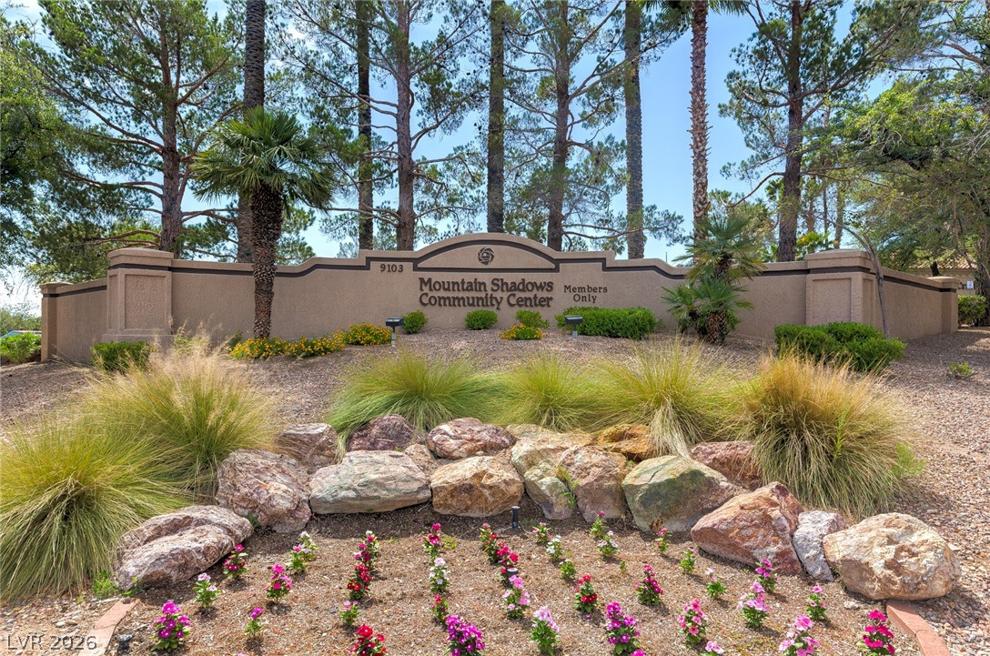 Mountain Shadows Community Center sign above desert landscaping and a flower bed.