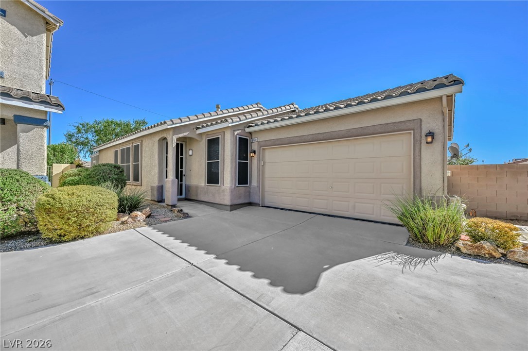 Single-story stucco home with a tiled roof, two-car garage, and desert landscaping.