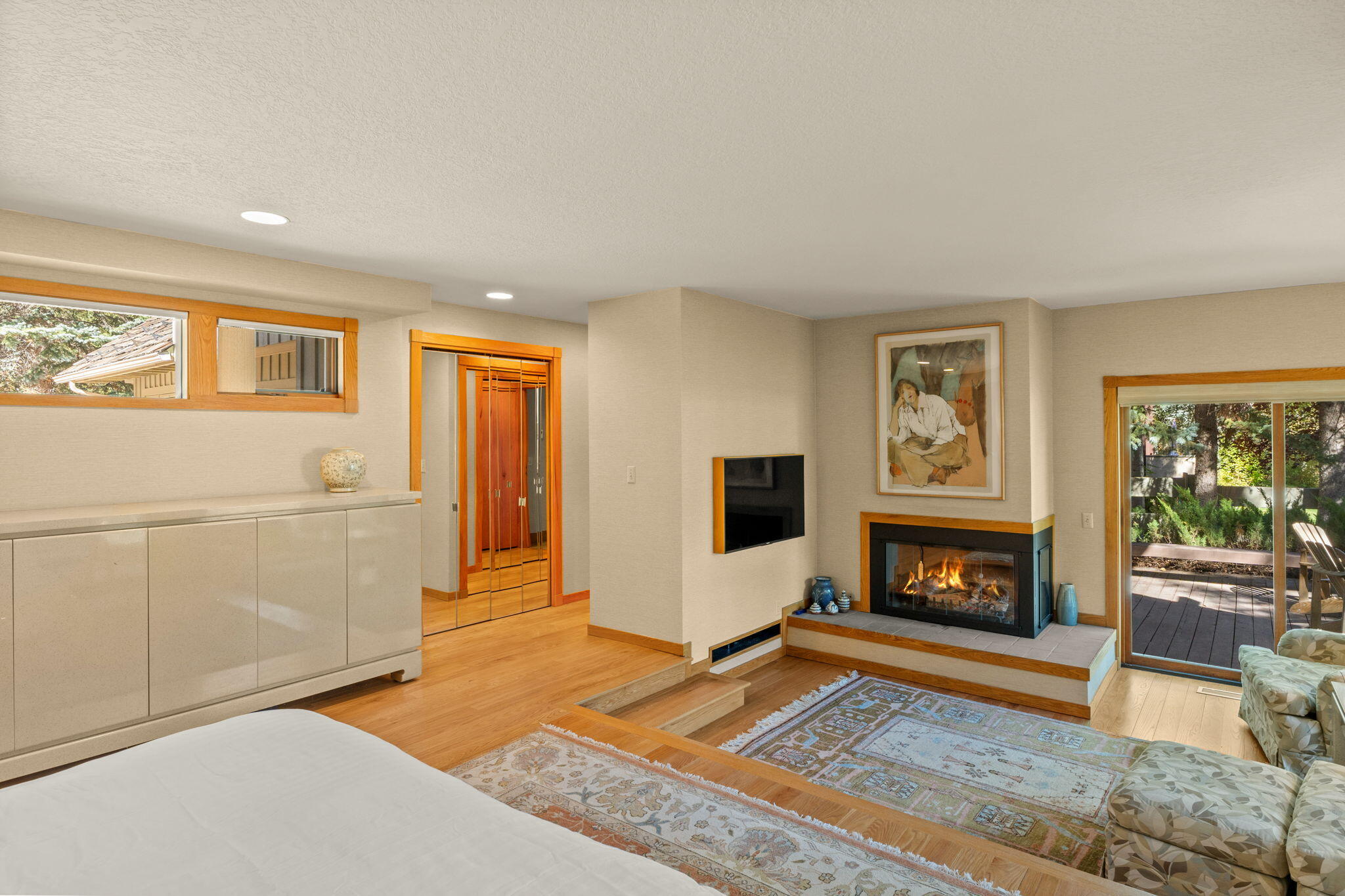 Bedroom with a fireplace, wood floors, and sliding doors to a deck.