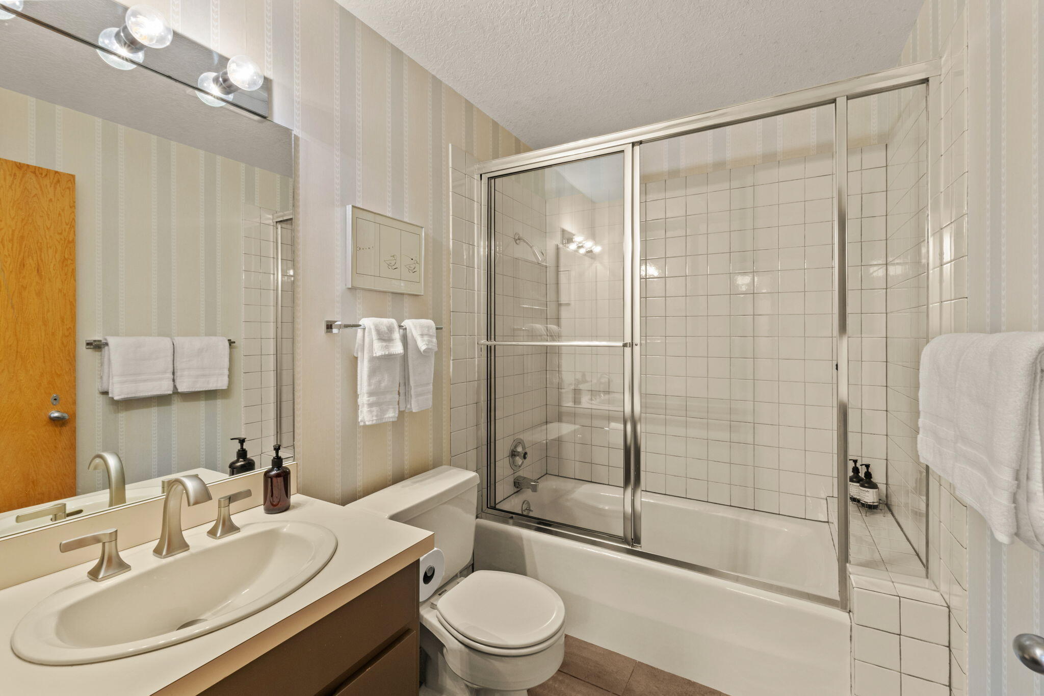 Bathroom with a wide vanity, toilet, and glass-enclosed tub and shower.