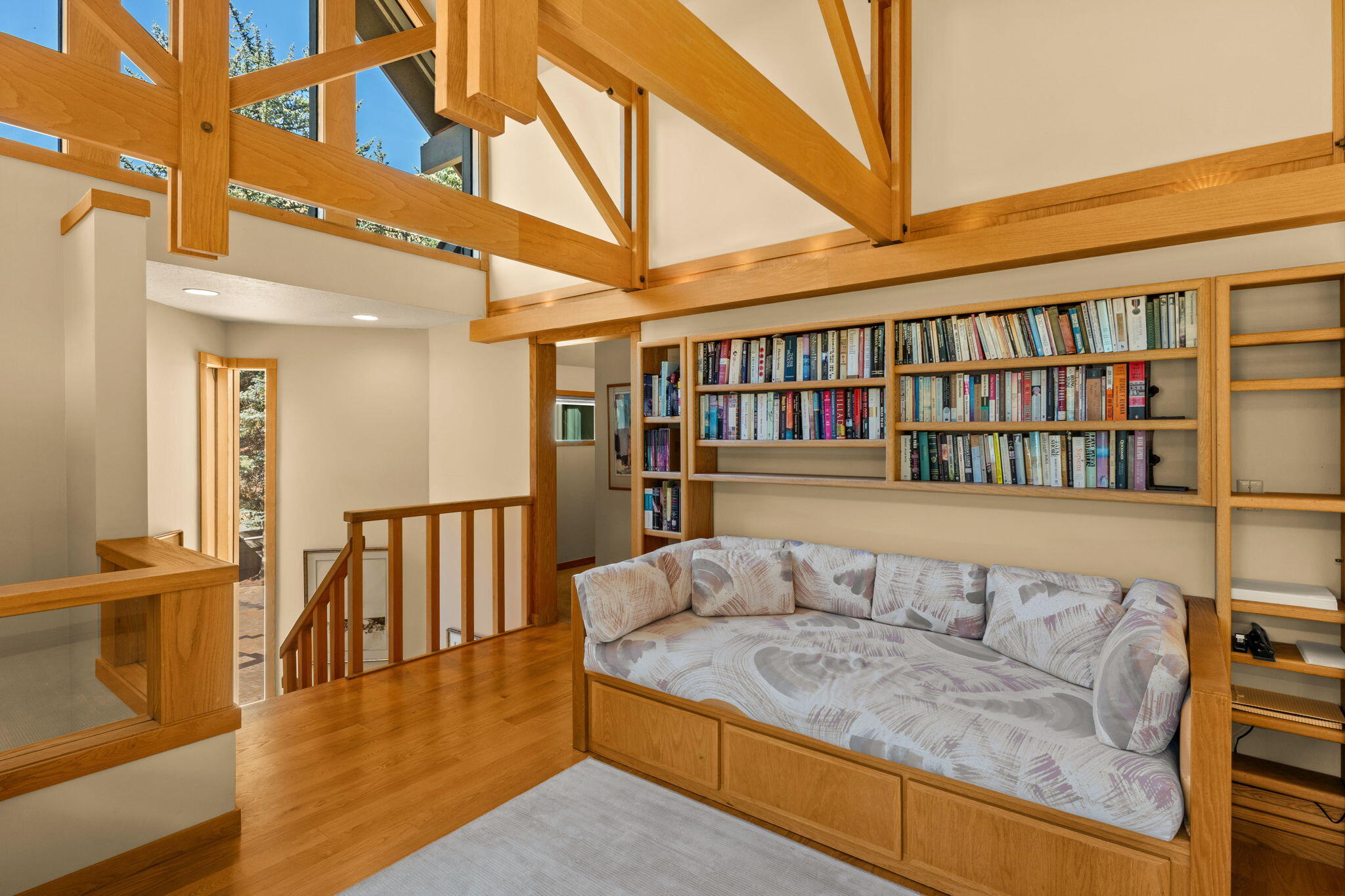Loft sitting area with built-in bookcases, cushioned bench, and exposed timber beams