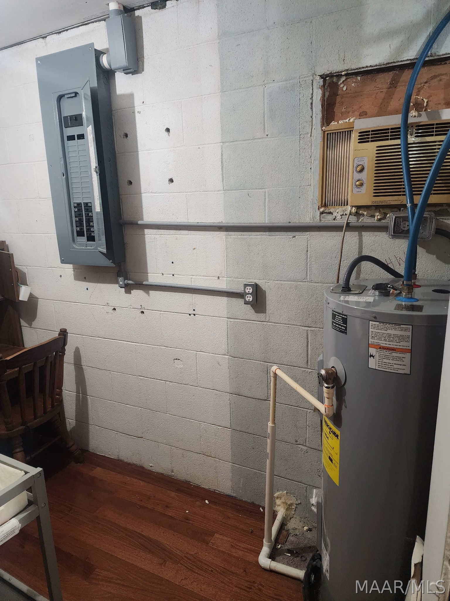 Utility area with a water heater, electrical panel, and window air conditioner.