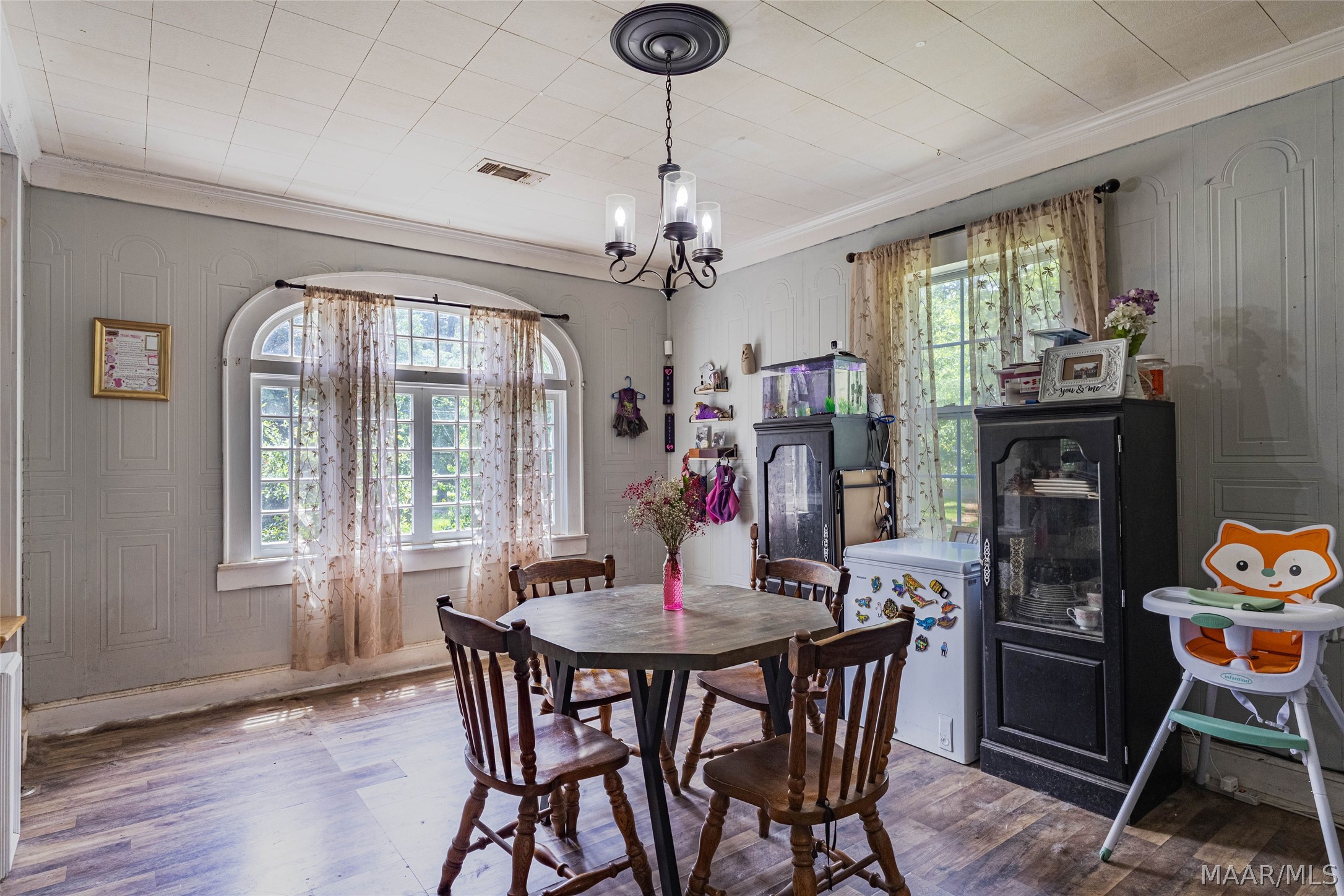 Dining room with a dark wood table, chandelier, and large arched window.