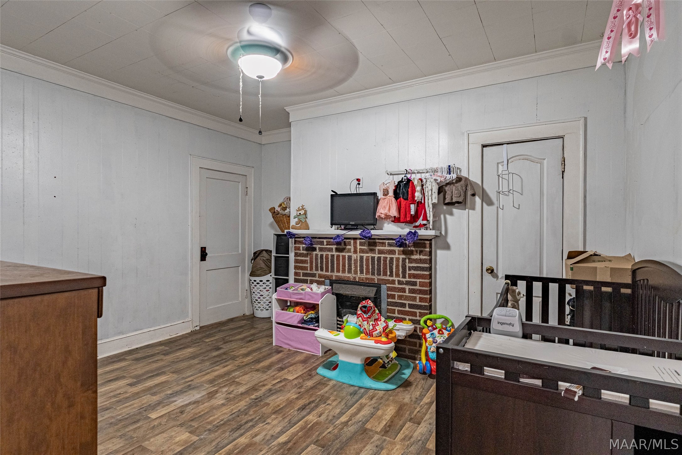 Nursery with a dark wooden crib, colorful toys, and a brick fireplace.