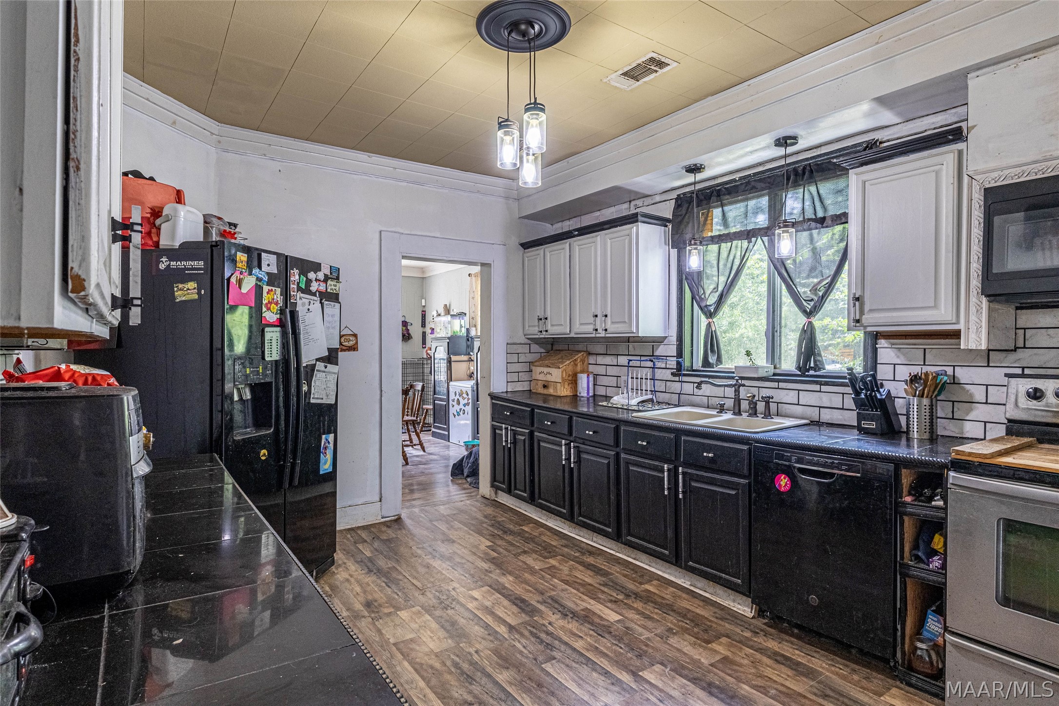 Kitchen with dark cabinets, white subway tile backsplash, and a large window over the double sink.