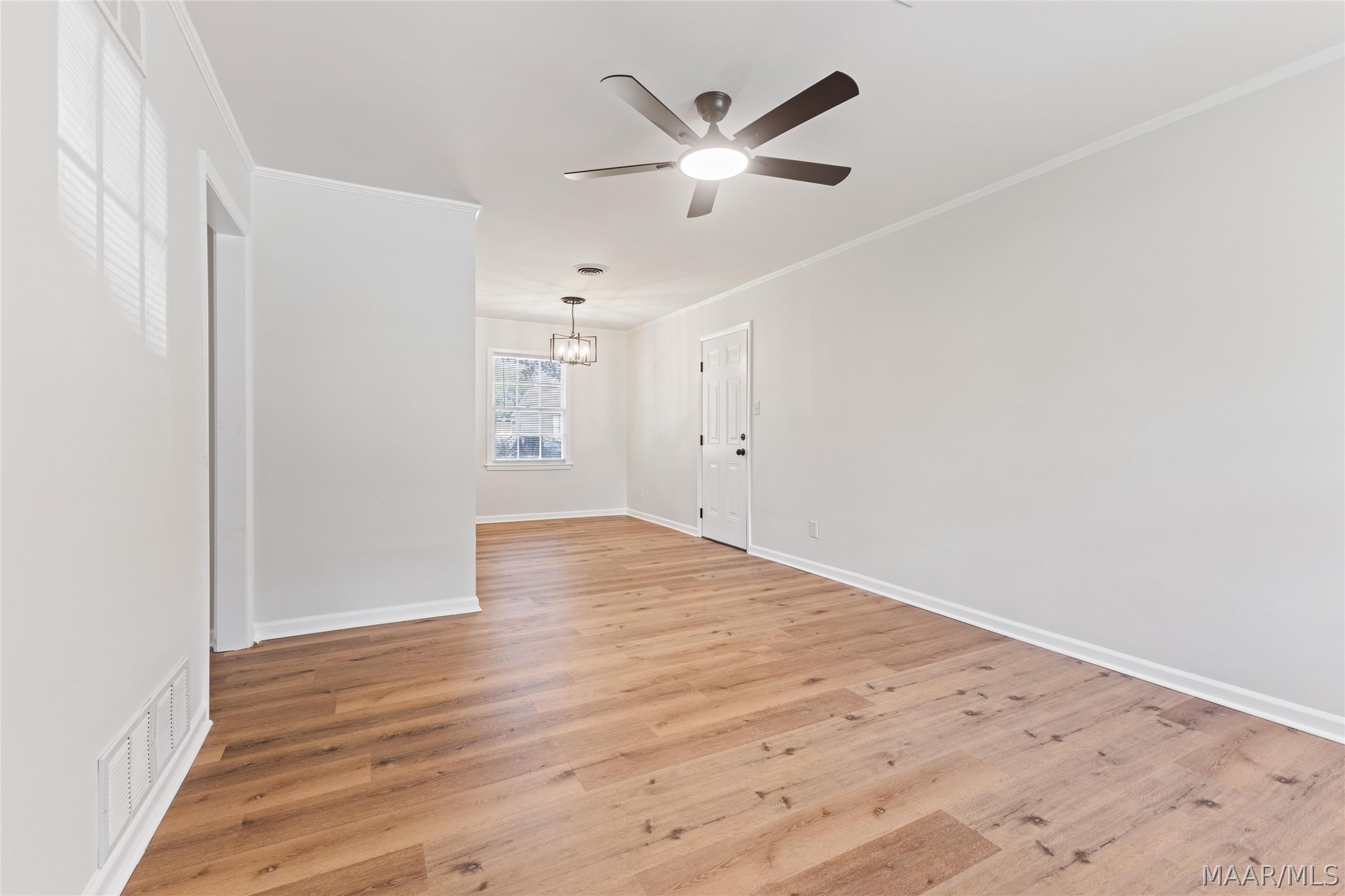 Empty room with light wood flooring, a ceiling fan, and a window beside the exterior door.