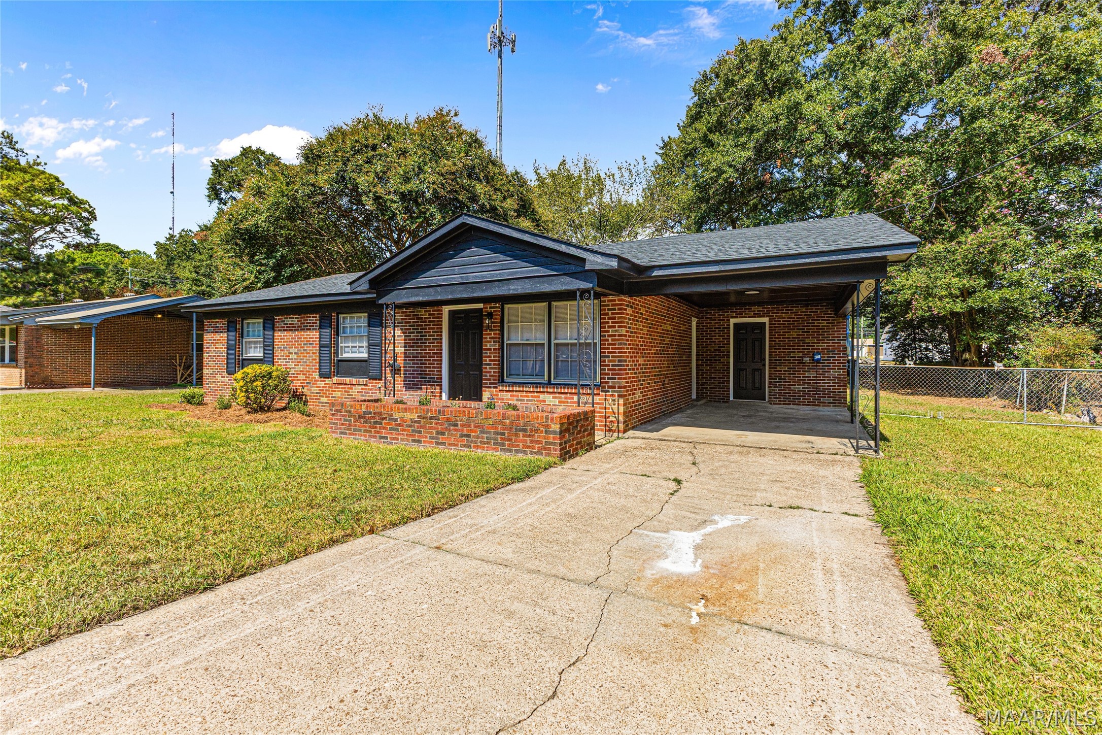 Red brick home with a covered carport, front porch, and concrete driveway.