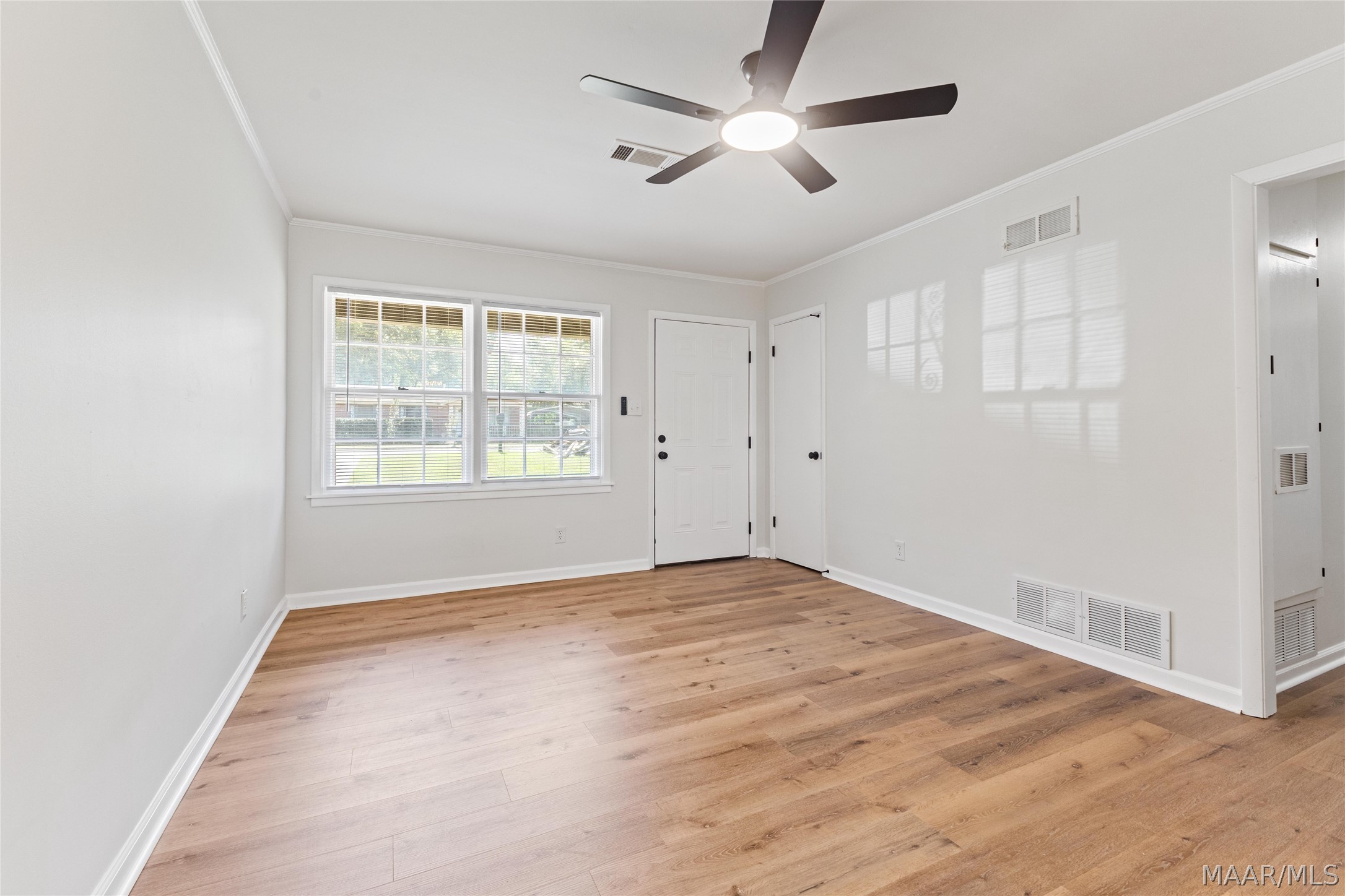 Empty room with wood floors, two windows, and a ceiling fan.