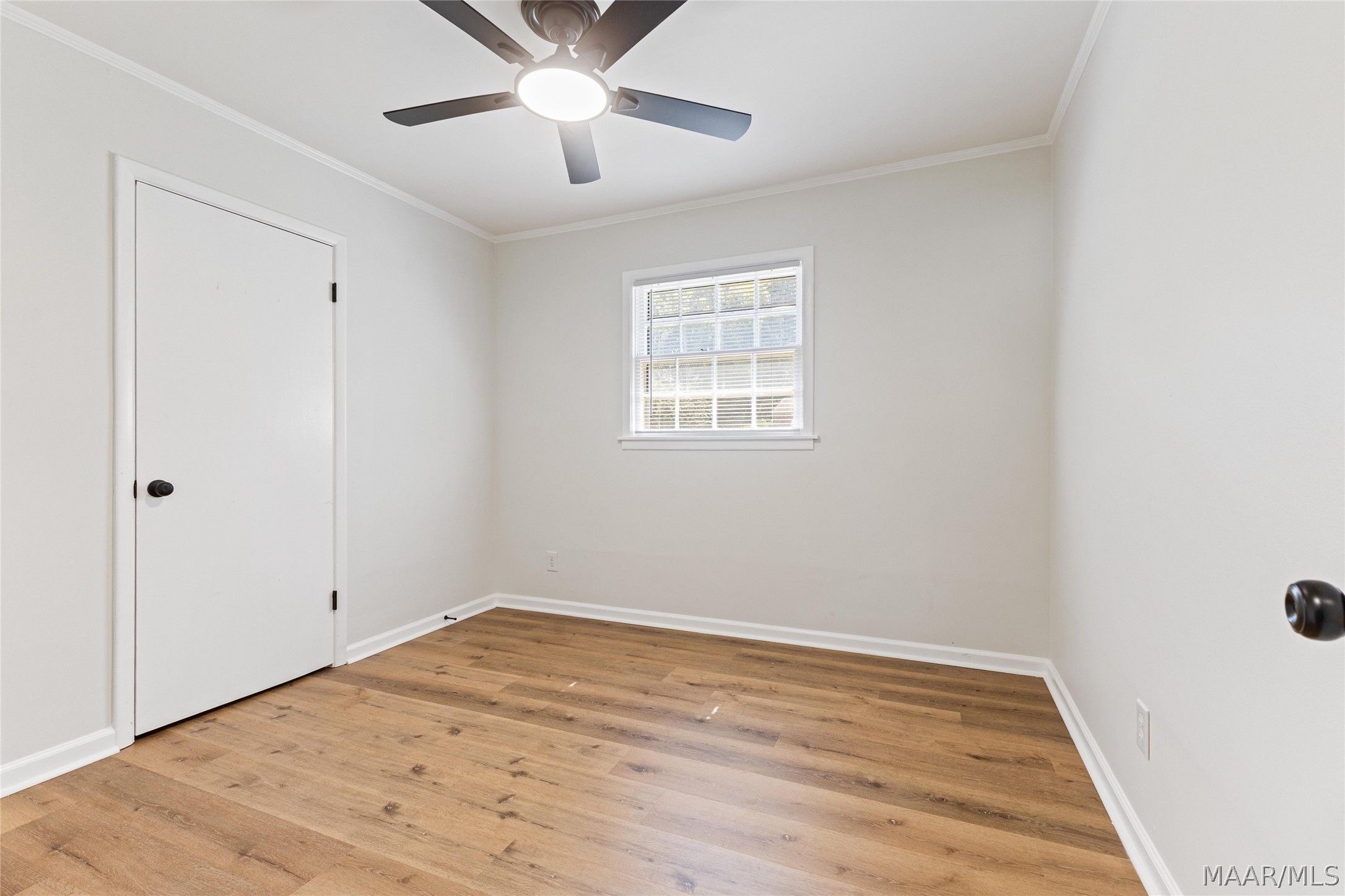 Empty bedroom with wood plank flooring, a ceiling fan, and a window with blinds.