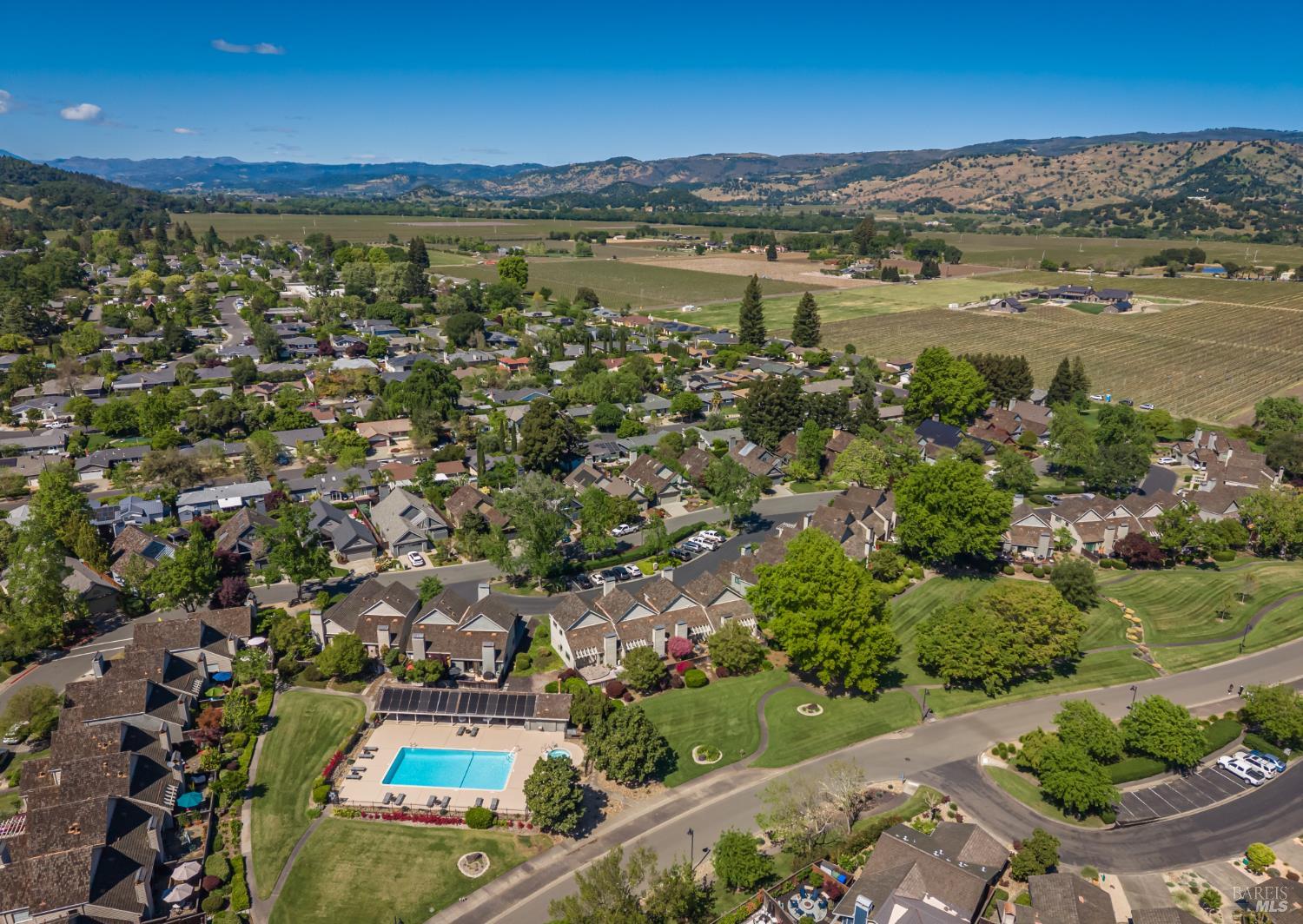 Aerial view of Yountville homes, a community pool, vineyards, and rolling hills.