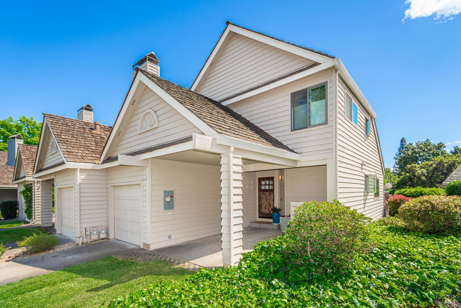 Two-story light-sided home with gabled roofs, two garage doors, and a covered entry.