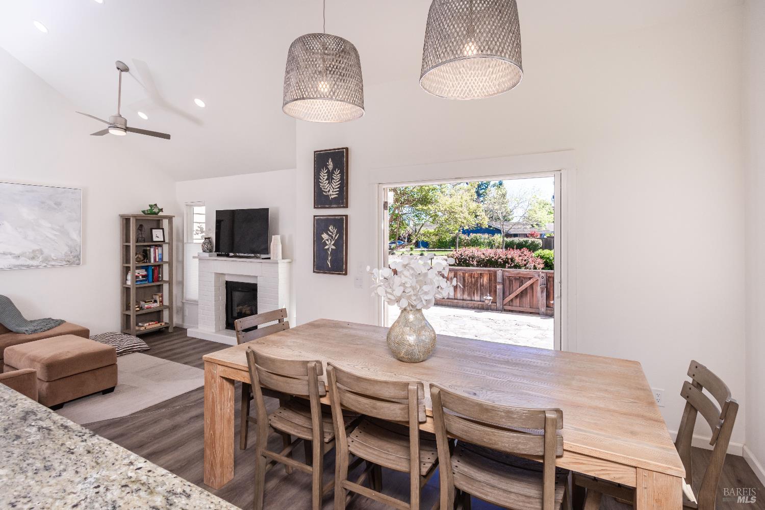 Dining and living area with a wooden table, white fireplace, and sliding doors to a patio.
