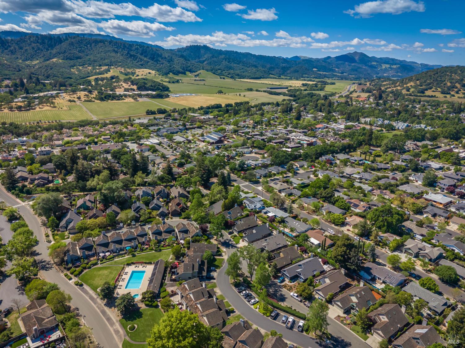 Aerial view of Yountville homes, with a swimming pool, vineyards, and hills in the distance.