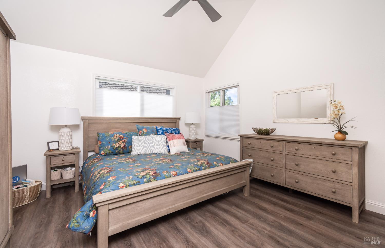 Bedroom with blue floral bedding, matching wooden furniture, and dark wood floors.