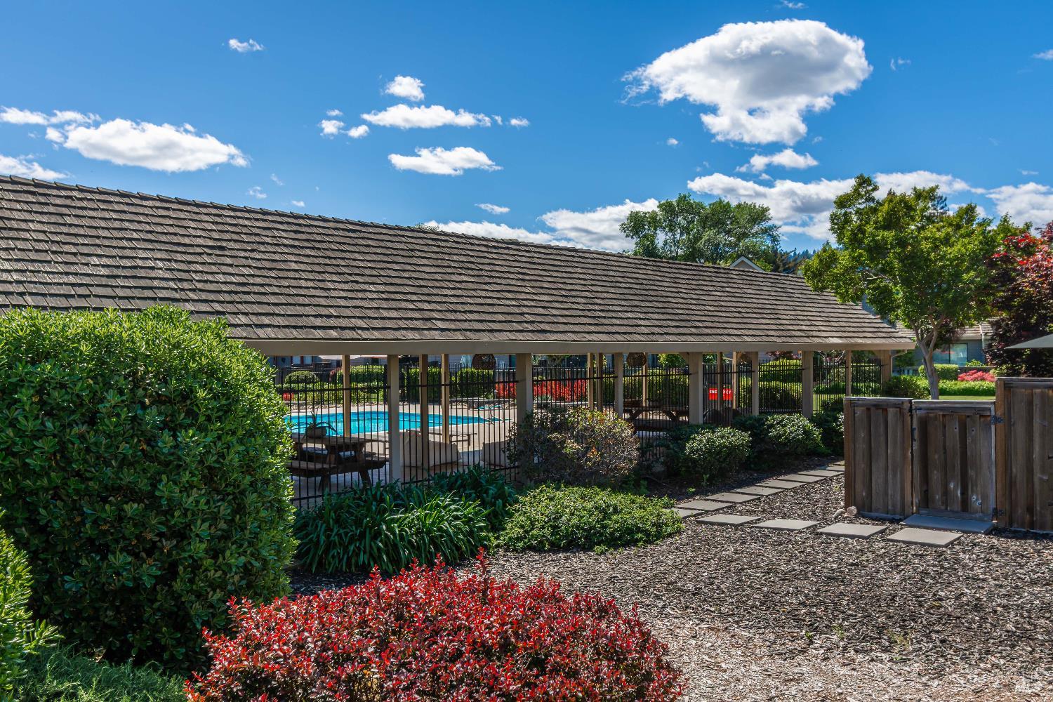 Community swimming pool behind a covered pavilion, surrounded by landscaping and a stepping-stone path.