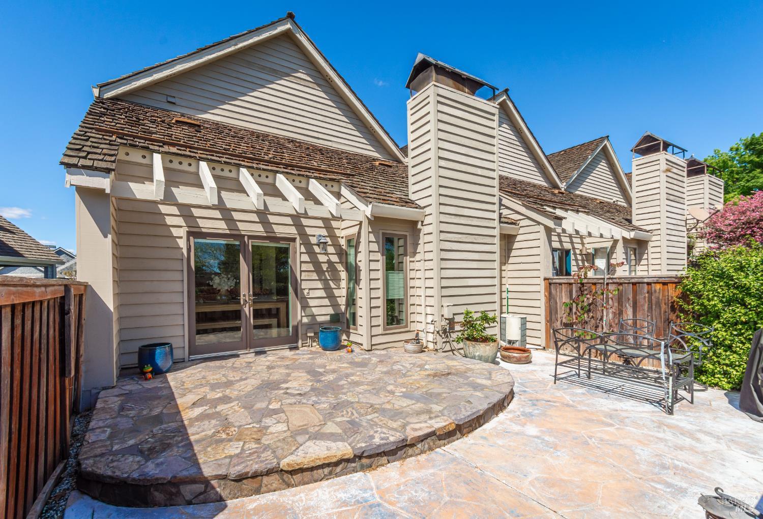 Home exterior with a broad stone patio, raised circular platform, and metal outdoor seating.
