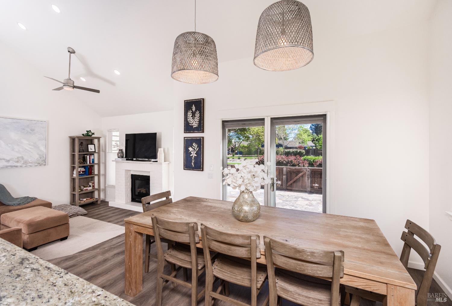 Dining area with a long wooden table, woven pendant lights, and sliding doors to the patio.