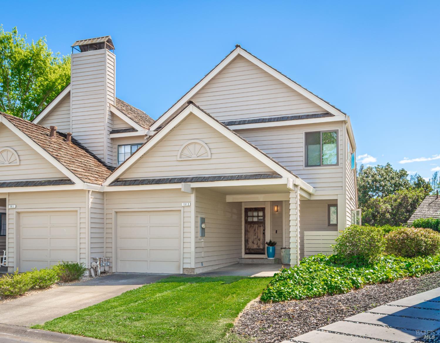 Two-story home with gabled roofs, two garage doors, a covered entry, and a landscaped front yard.