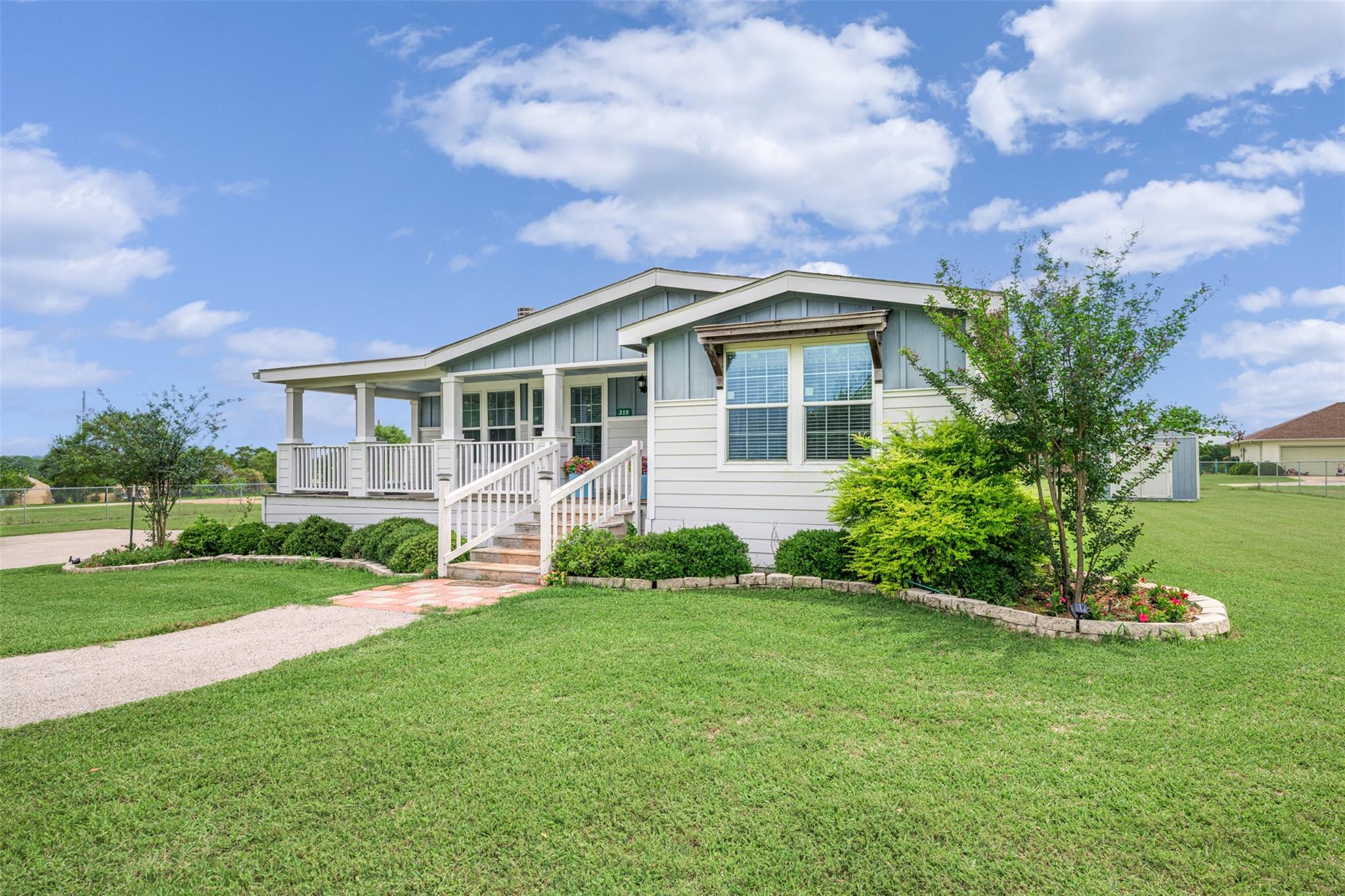 House with a covered porch, white railings, and landscaped lawn.