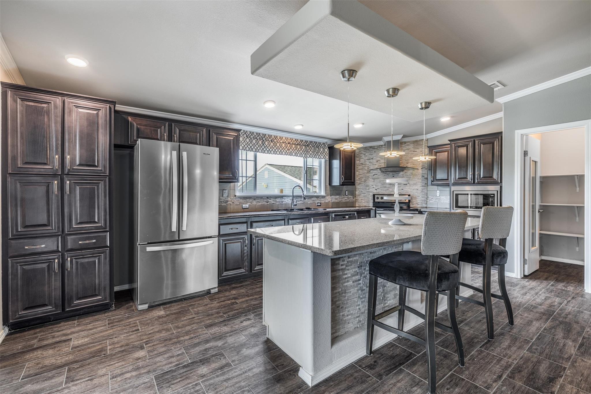 Kitchen with dark cabinets, stainless steel appliances, and a large island with bar seating.