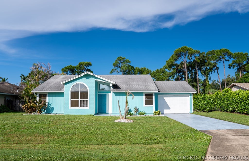 Turquoise single-story house with an arched front window, white garage, and broad lawn.