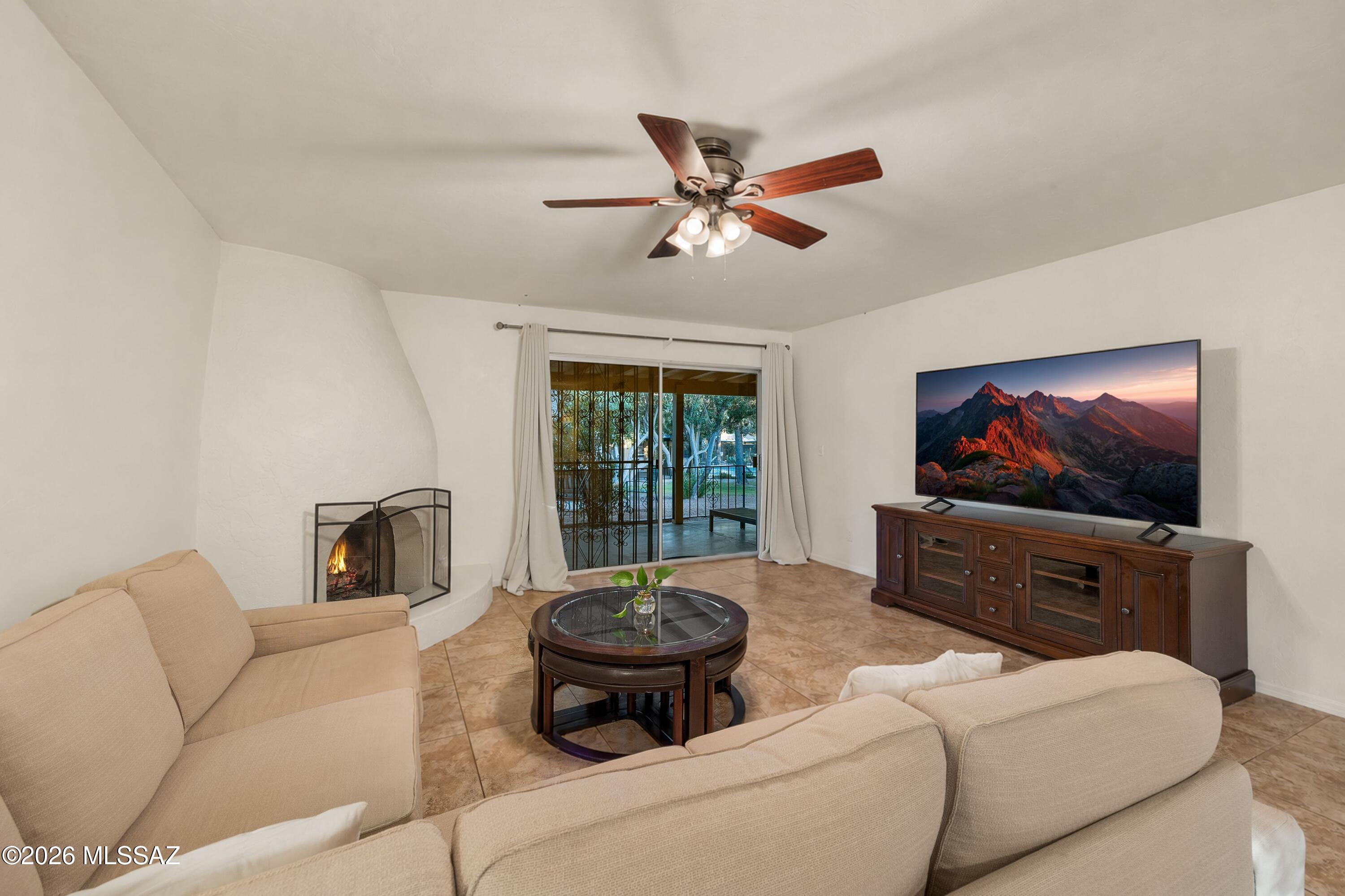 Living room with beige sofas, a fireplace, and sliding glass doors opening to a covered patio.