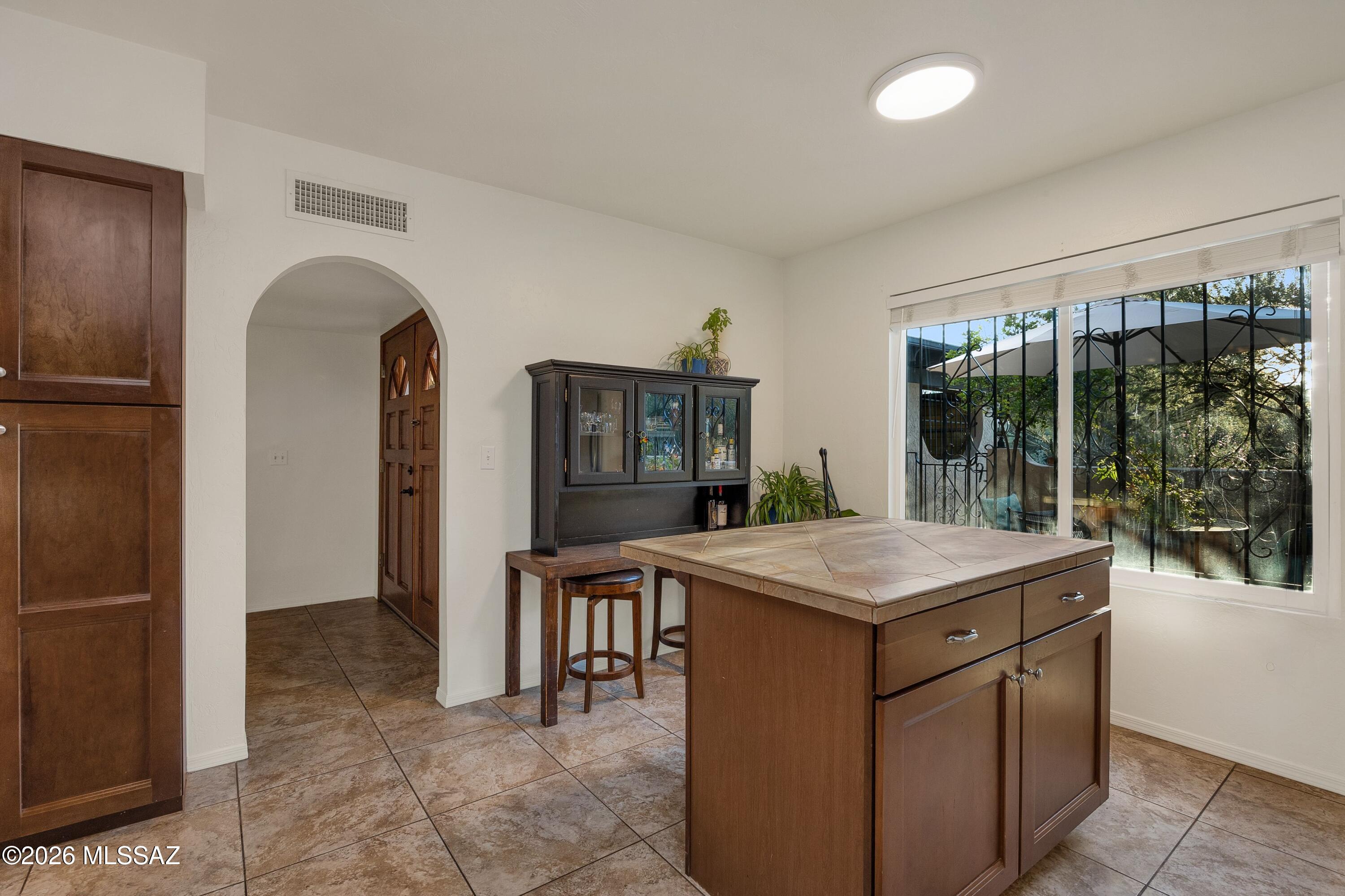 Kitchen with a tiled wooden island, dark cabinetry, and a large barred window.