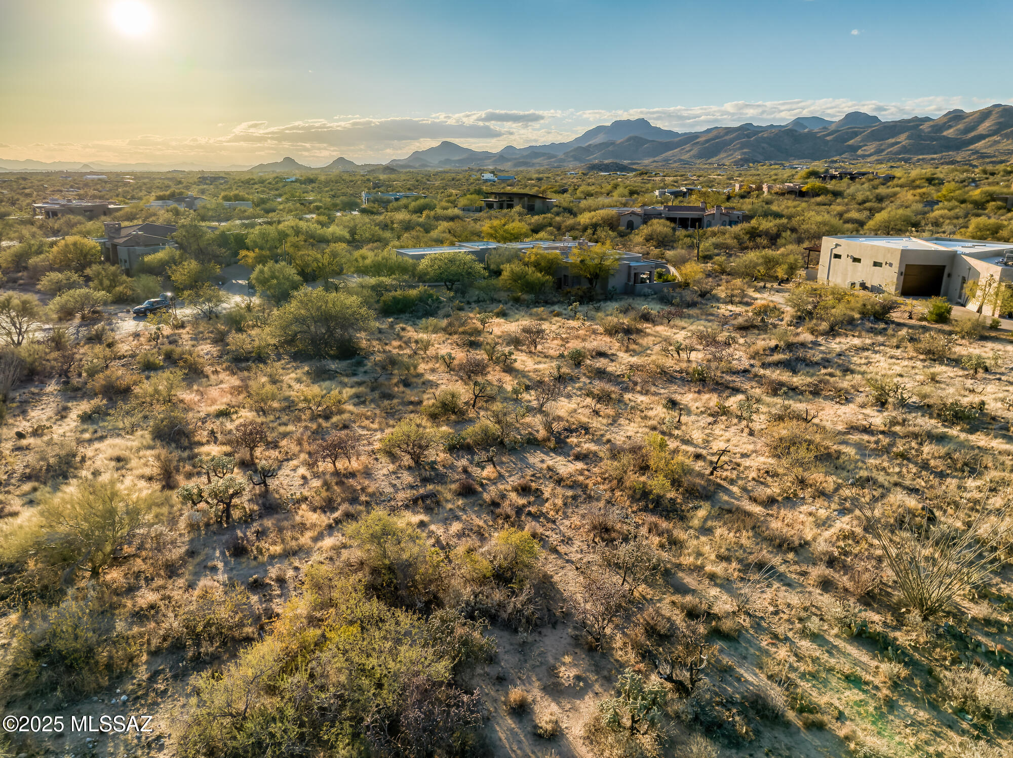 Aerial view of desert homes and scrubland with mountains in the distance.