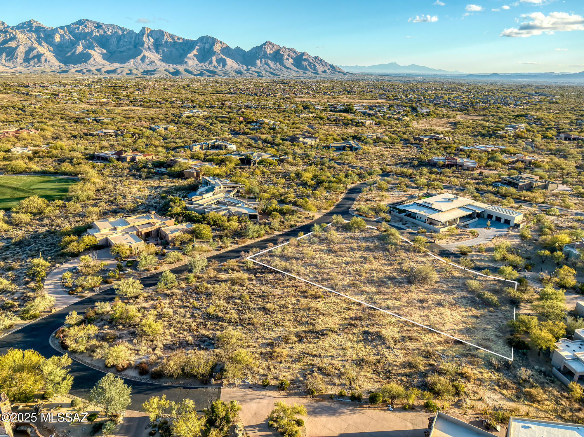 Vacant desert lot outlined in white, with nearby homes and mountains in the distance.