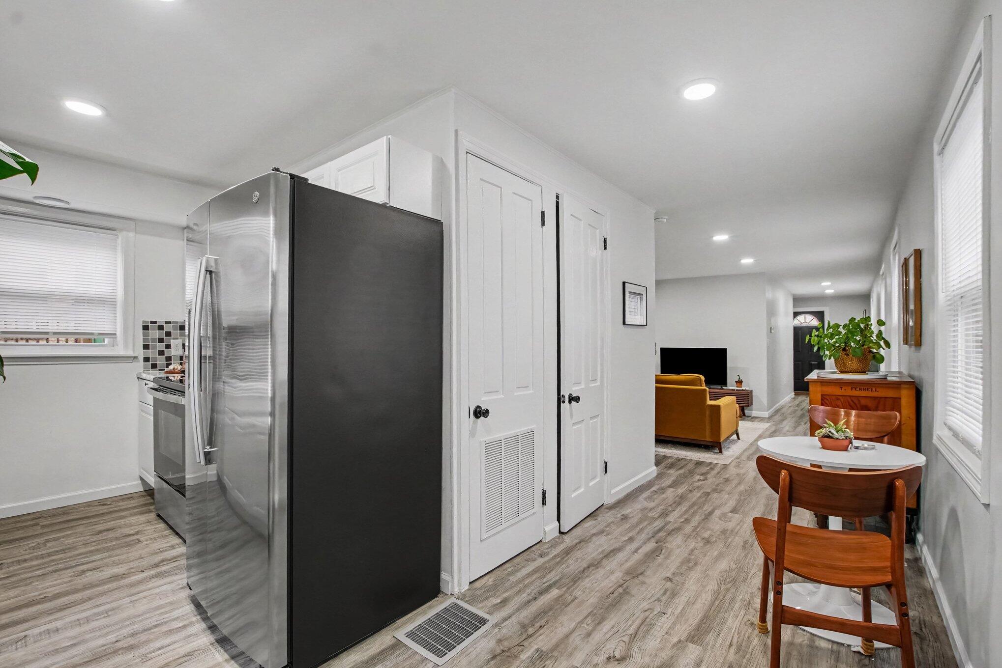 Furnished kitchen and dining area with a large stainless-steel refrigerator, round table, and wood-look floors.