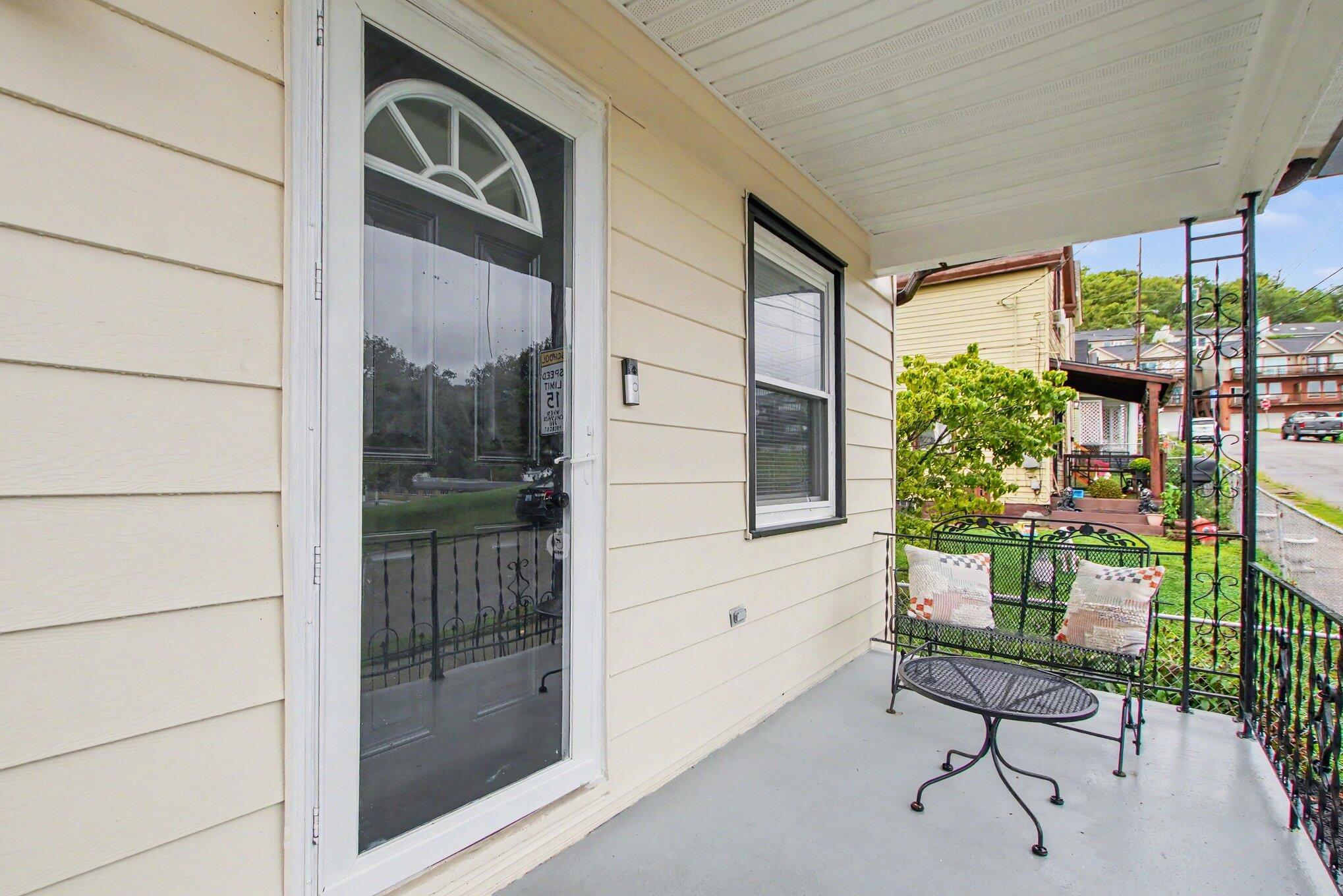 Covered front porch with a half-circle window over the entry door and black metal seating.