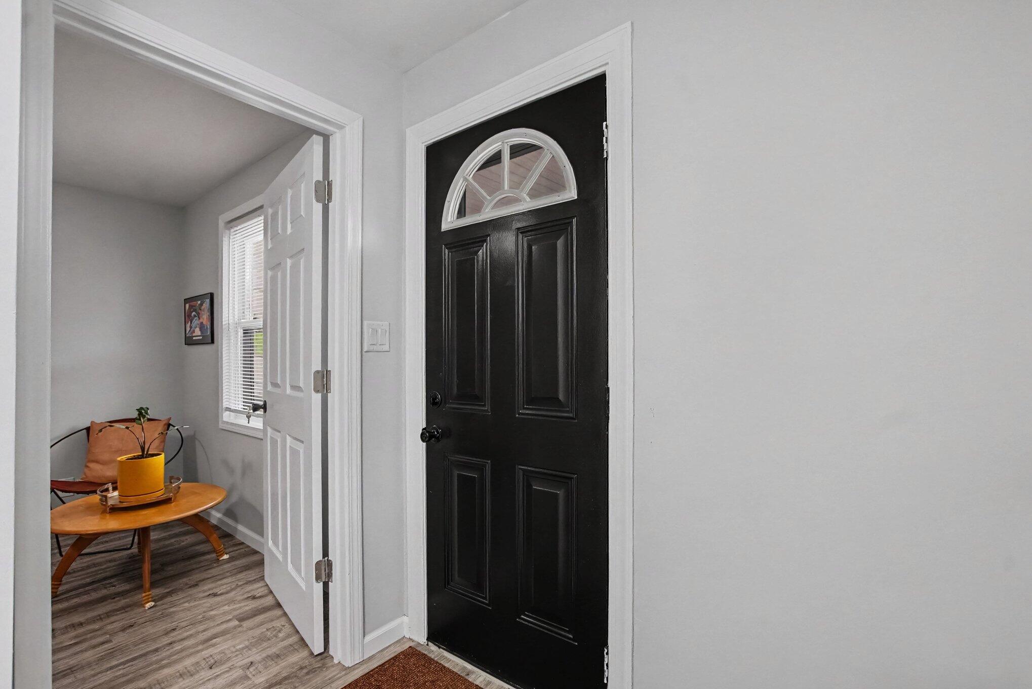 Entryway with a black front door and a small furnished sitting nook.