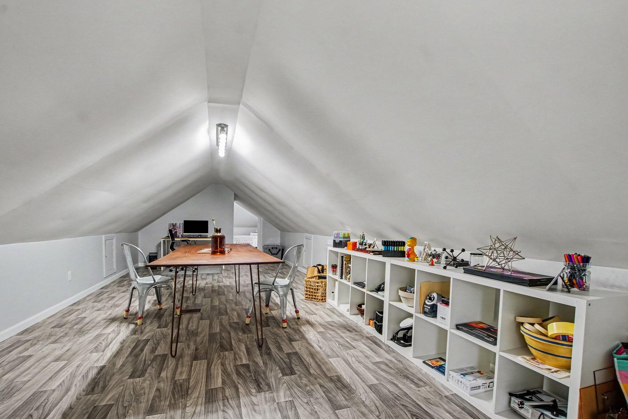 Finished attic workspace with a central table and long shelves of art supplies.