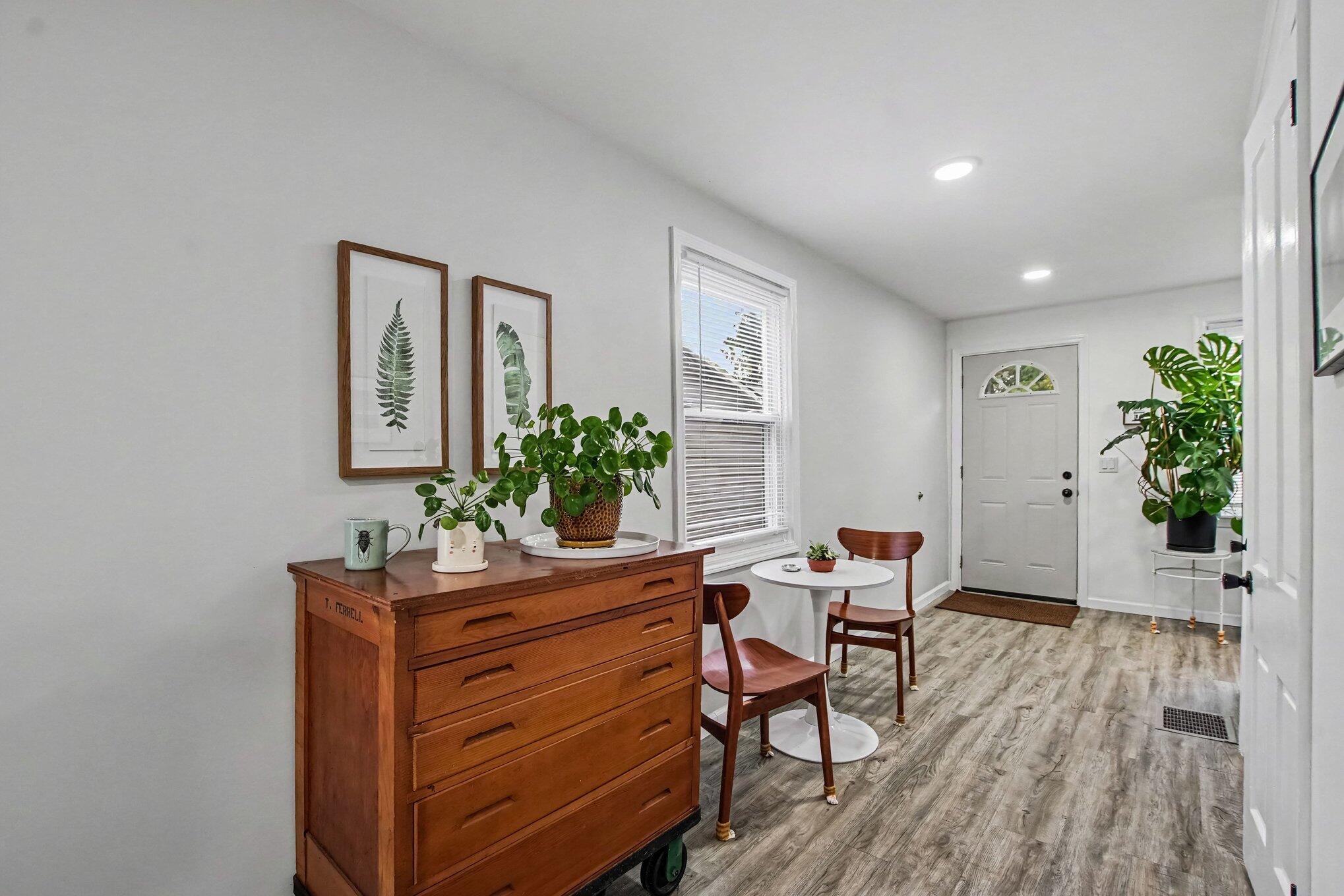 Furnished entryway with a wooden chest, potted plants, and a small table with two chairs.