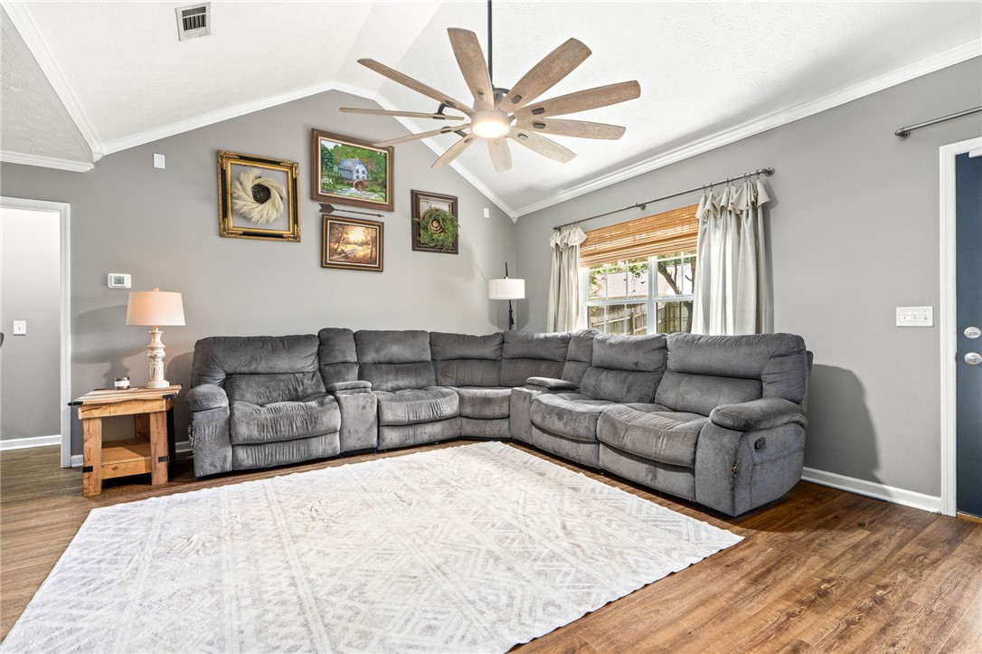 Living room with a gray sectional sofa, large window, and hardwood floors.