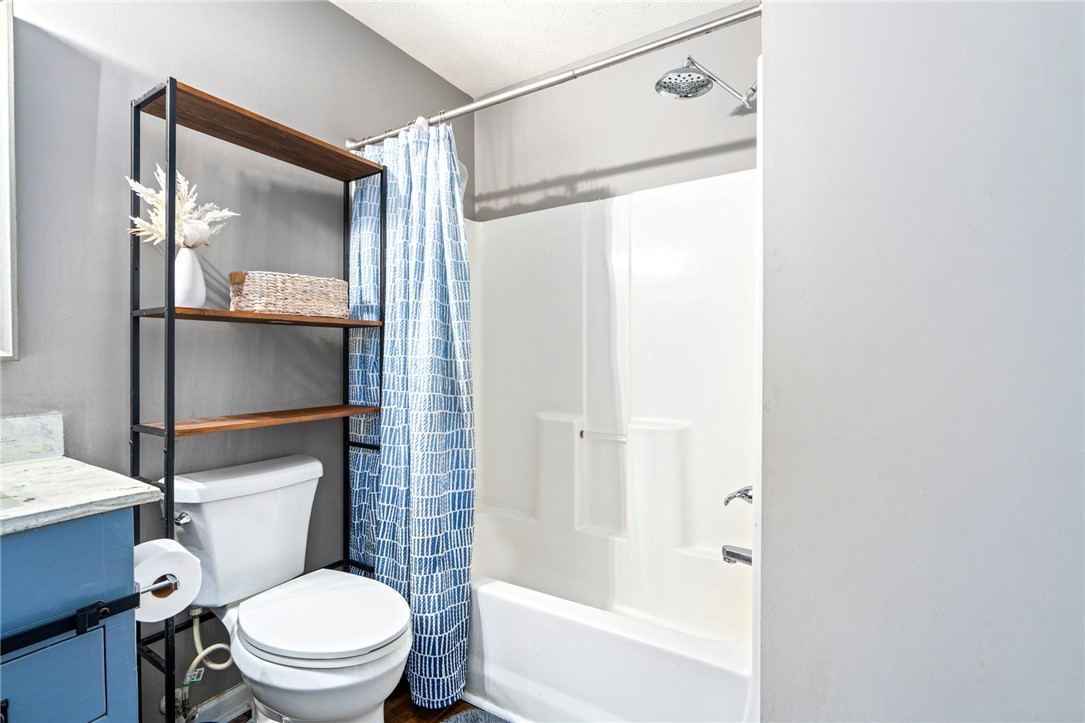 Bathroom with a blue vanity, white tub and shower, and blue patterned curtain.