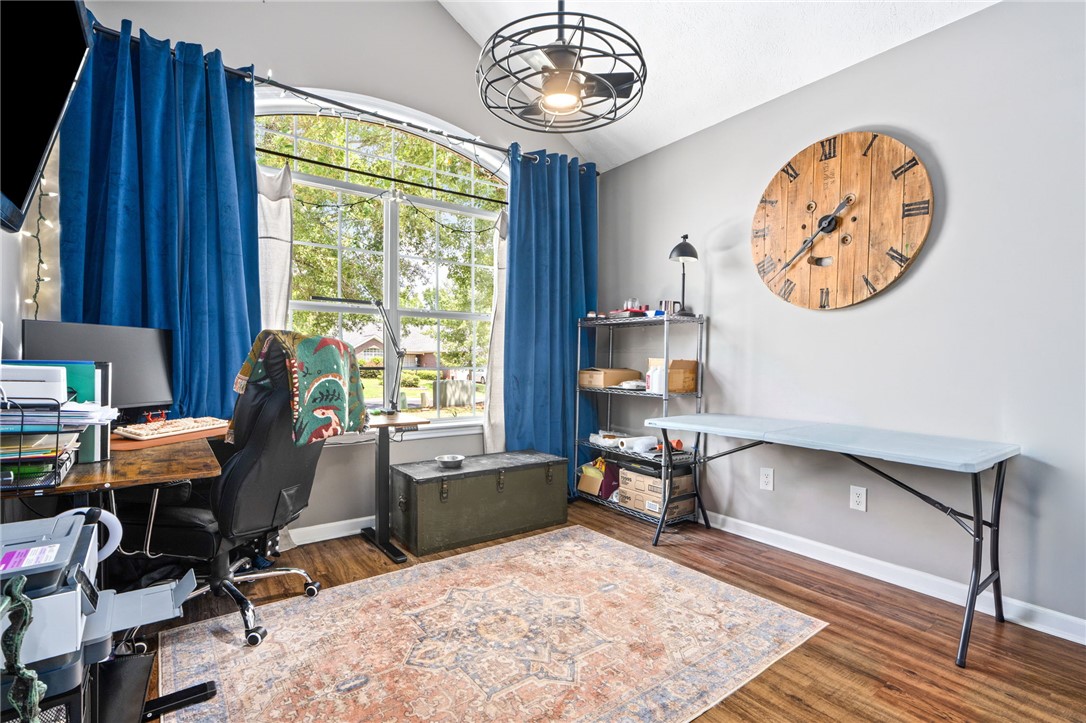 Home office with a tall arched window, blue curtains, and a large wooden wall clock.