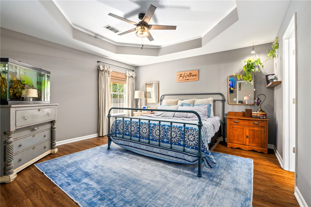 Bedroom with an iron bed, blue patterned bedding, and a tray ceiling.