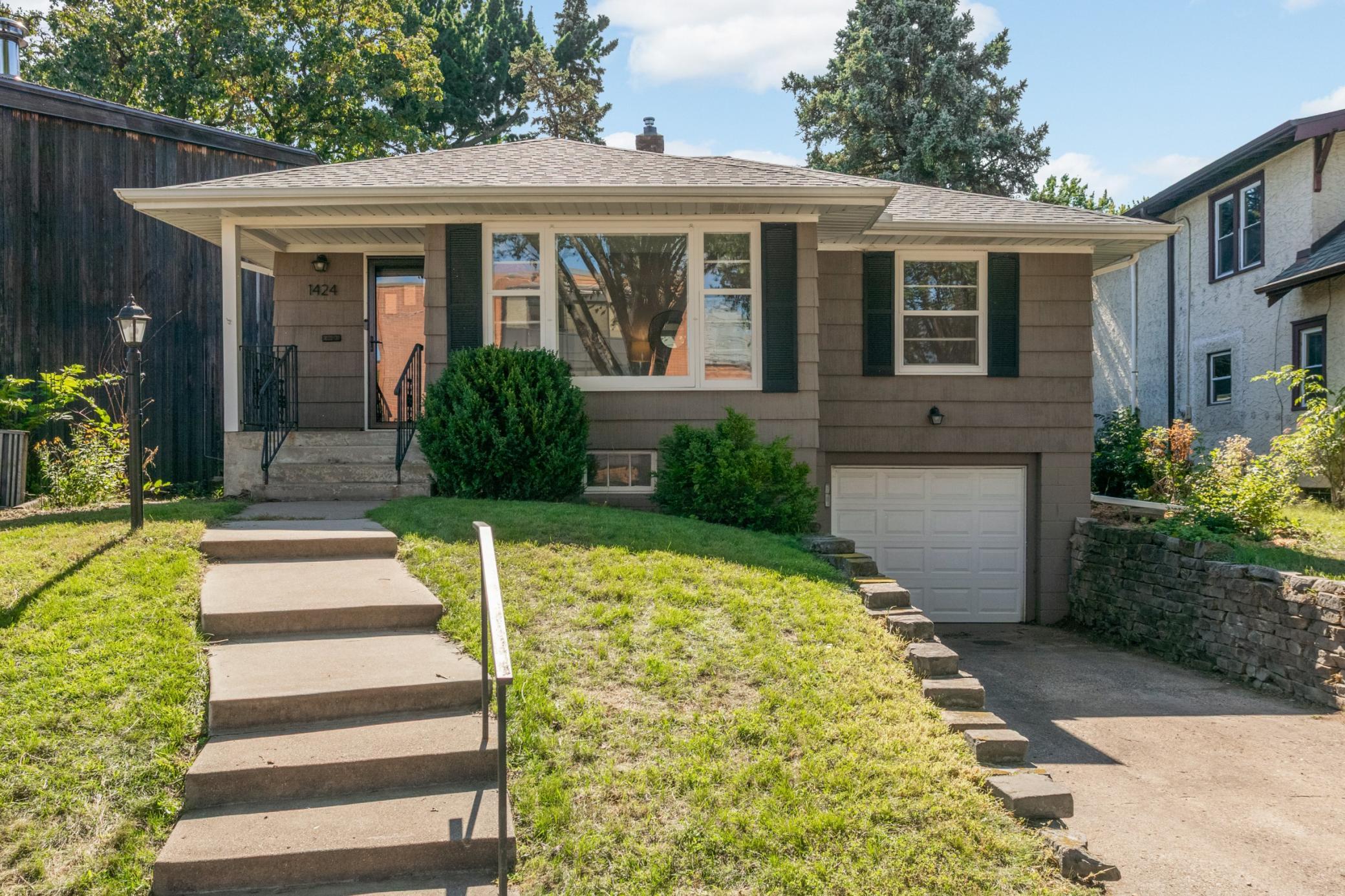 Brown split-level house with front steps, dark shutters, and an attached garage.