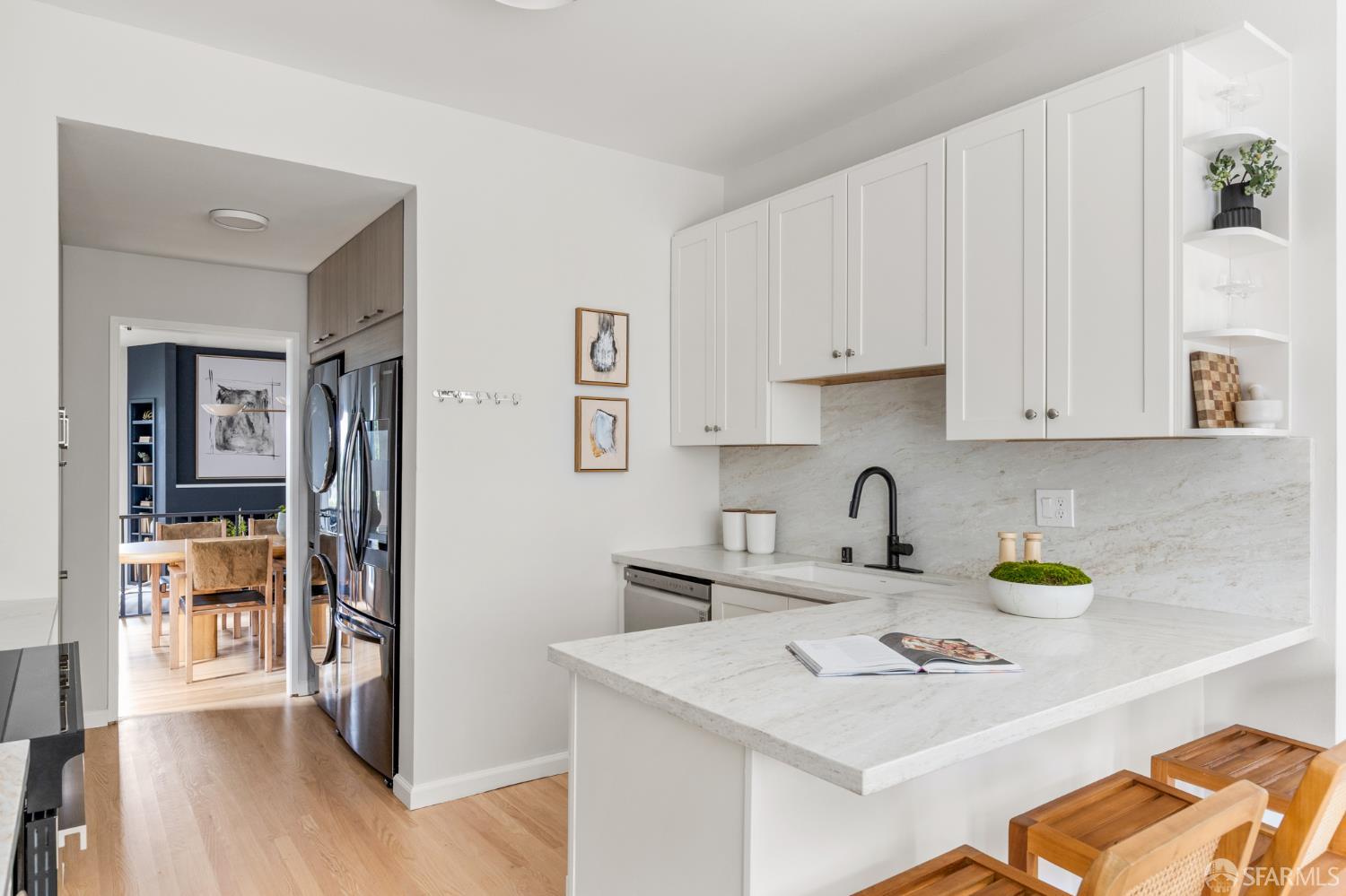 Bright kitchen with white cabinetry, a stone peninsula, and a dining area beyond the doorway.