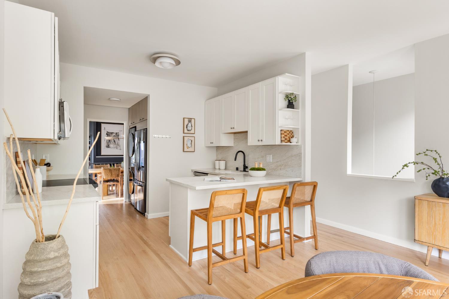 Bright kitchen with white cabinets, a stone island, and three wooden stools.