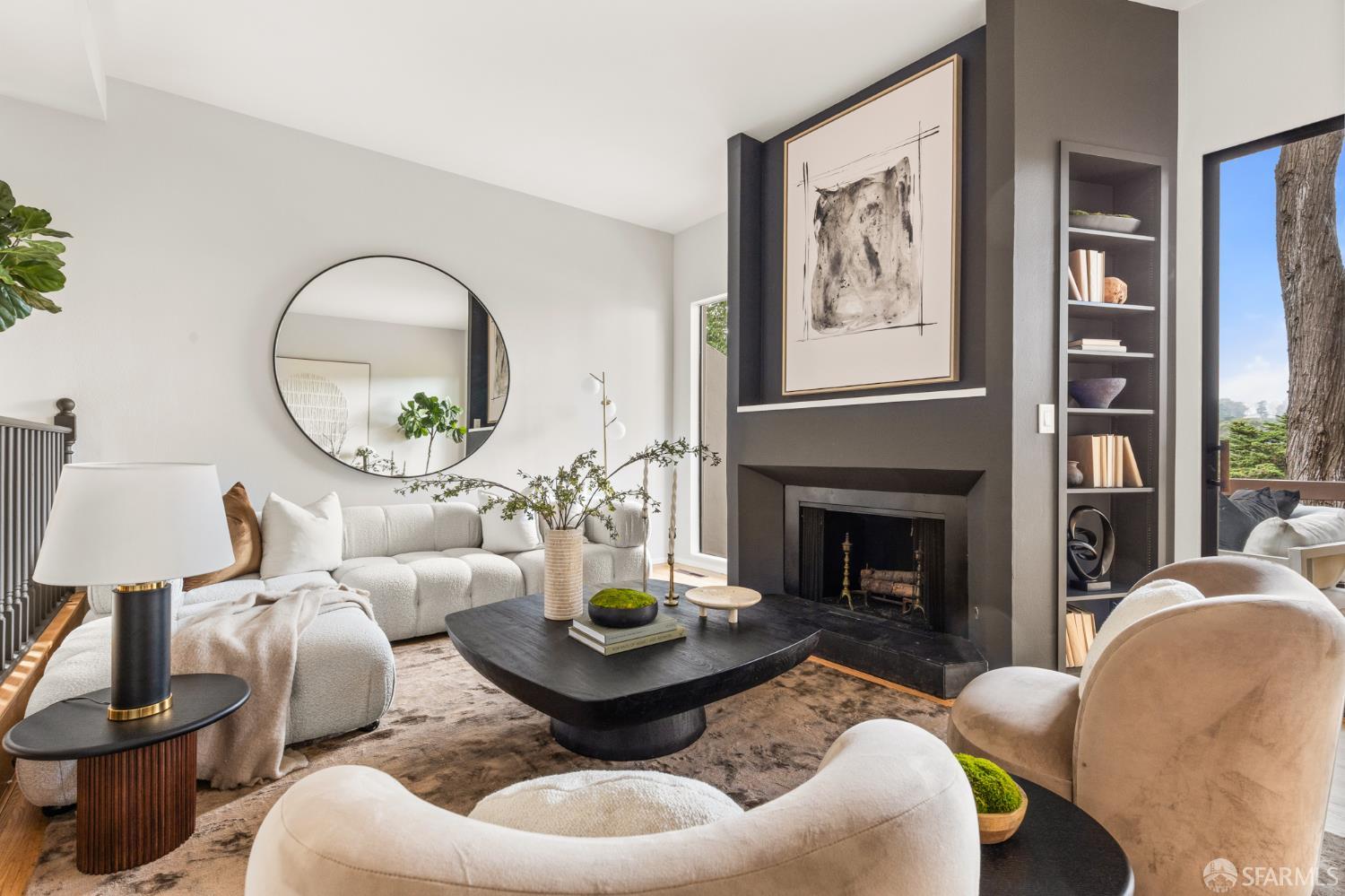 Staged living room with a charcoal fireplace wall, built-in shelves, and curved cream seating.