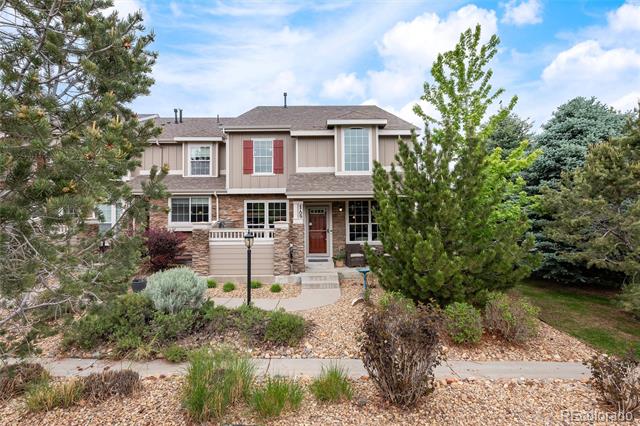 Two-story house with stone accents, red shutters, and a gravel-landscaped front yard.