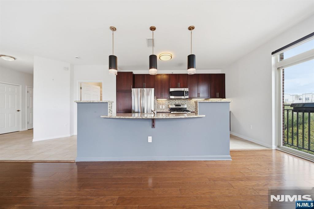 Kitchen with dark wood cabinets, stainless appliances, a raised breakfast bar, and a balcony door.