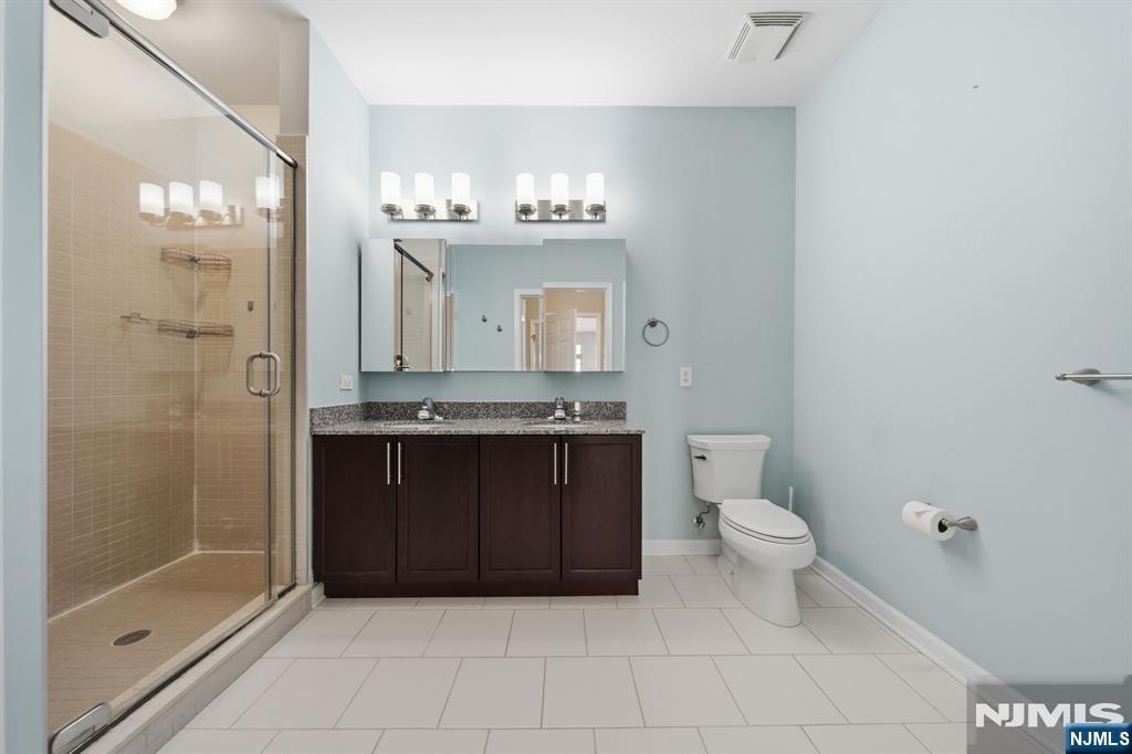 Bathroom with glass-enclosed shower and dark wood double vanity.