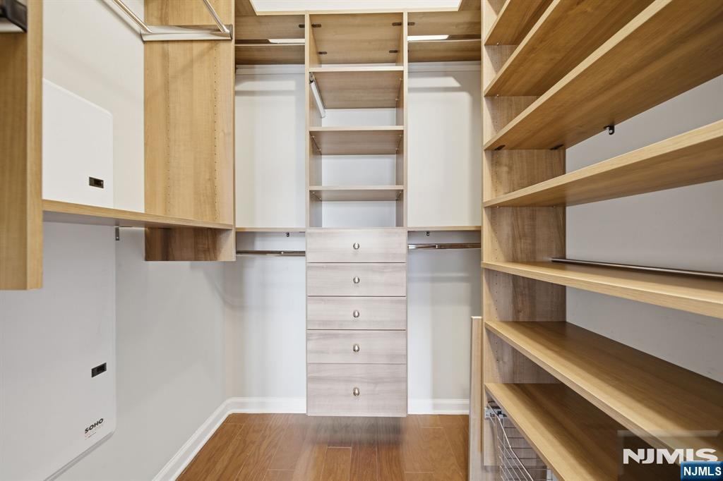 Walk-in closet with custom wood shelving, drawers, and hanging rods.