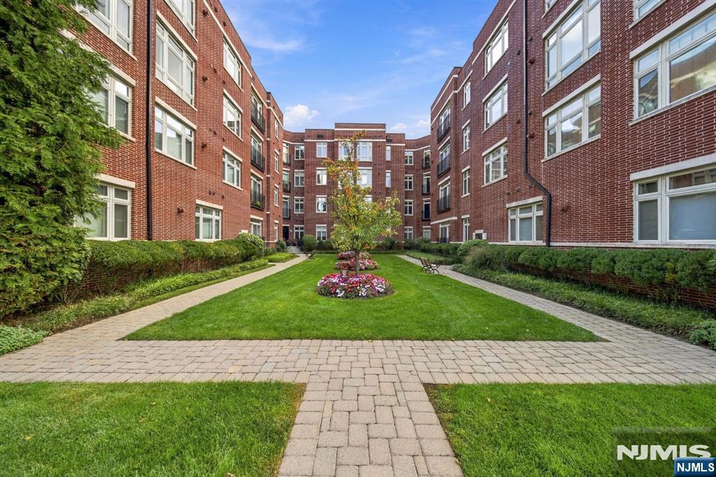 Apartment building courtyard with a central flower bed and paved walkways.