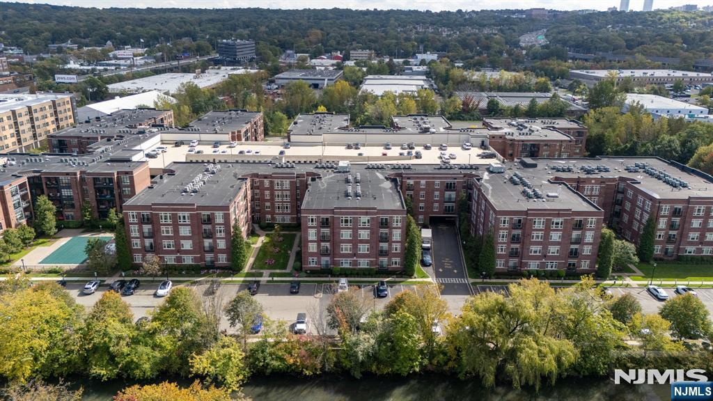 Aerial view of brick apartment buildings beside a river, with landscaped grounds and parking.